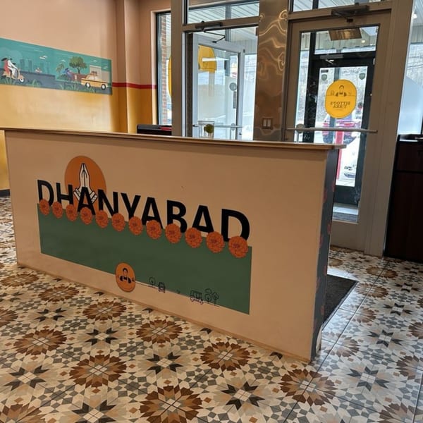 Bittoo's Tikka reception desk with "DHANYABAD" in large letters, marigold flowers, and patterned floor.