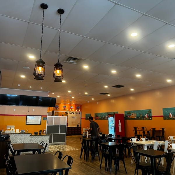 Interior of Bittoo's Tikka, an Indian restaurant, with tables, chairs, and a person walking.