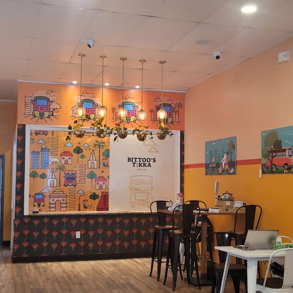 Bittoo's Tikka restaurant interior with colorful Indian-themed murals, pendant lights, and high-top tables.