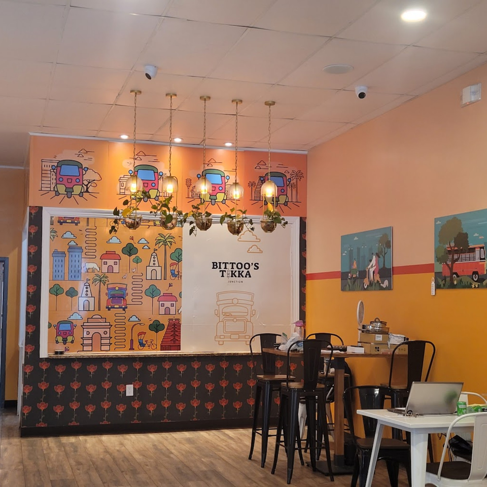 Bittoo's Tikka restaurant interior with colorful Indian-themed murals, pendant lights, and high-top tables.