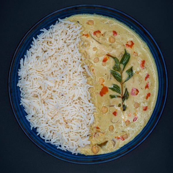 Bittoo's Tikka chickpea curry with rice, garnished with red peppers and green leaves.