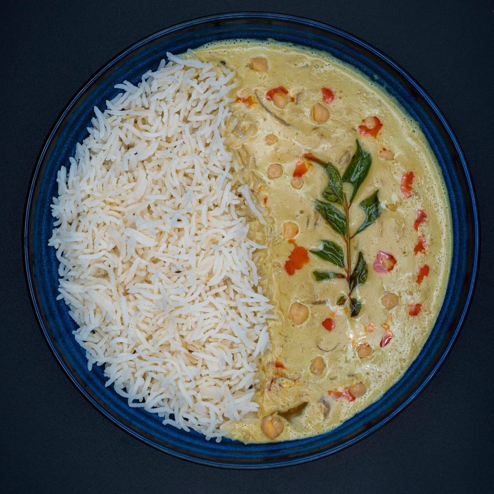 Bittoo's Tikka chickpea curry with rice, garnished with red peppers and green leaves.